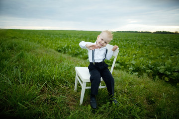 Naklejka na ściany i meble boy sits on chair in the field