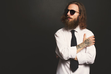 Close up stylish gorgeous young  businessman with long beard with glasses on black background