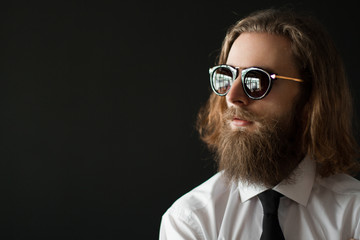 Close up stylish gorgeous young  businessman with long beard with glasses on black background