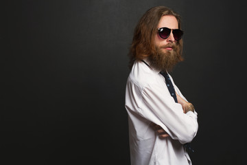 Close up stylish gorgeous young  businessman with long beard with glasses on black background