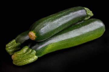 Stack of whole courgettes isolated on black.