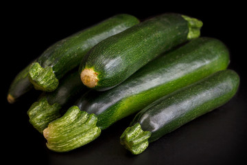 Stack of whole courgettes isolated on black.