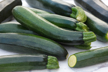 Pile of whole courgettes on white weathered wood.
