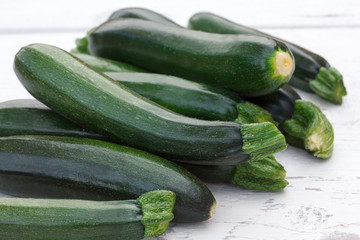 Pile of whole courgettes  on white weathered wood.