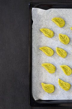 Raw leaf-shaped matcha cookies on the baking sheet