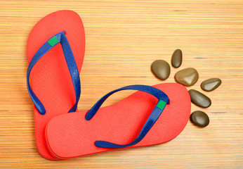 red flip-flops and pebbles on the wooden background