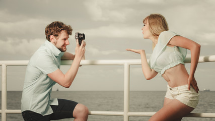 Young couple in love is taking photos on sea pier.