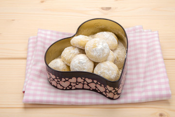 Fototapeta na wymiar Small cookies homemade in powdered sugar in a tin box in heart shape on cotton checkered napkin