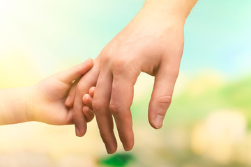 Child and mother hands together on bright background