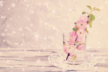 Beautiful fruit blossom in glass on table on light background