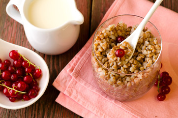Breakfest with buckwheat porridge, milk and red currant berries