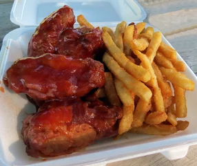Badkamer foto achterwand Take-out chicken wings in barbeque sauce and French fries for a picnic in the park. © Nik's Pics