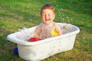 A small happy baby bathed in the bath and playing in a bath with