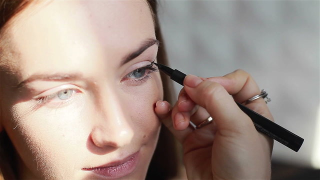 Professional make-up artist applying eyeliner. Close-up