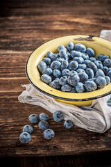 Gardening blueberries in a simple rustic bowl on dark wooden background