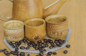 Soft focus image of coffee beans and coffee cups set on wooden b