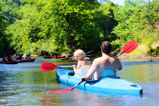 Father and son kayaking on the river. Active happy family, a man with teenage school boy, having fun together enjoying adventurous experience on a sunny day during summer vacation.