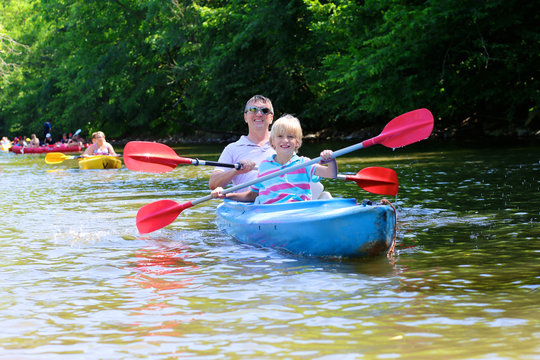 Father and son kayaking on the river. Active happy family, a man with teenage school boy, having fun together enjoying adventurous experience on a sunny day during summer vacation.
