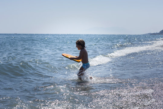 Ni&ntilde;o con tabla de surf en la orilla del mar