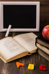 Back to school concept. Blackboard with a chalk, old books, apple and plastic letters. Vintage style. Selective focus