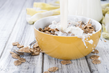 Obraz na płótnie Canvas Pouring Milk in a bowl with Cornflakes