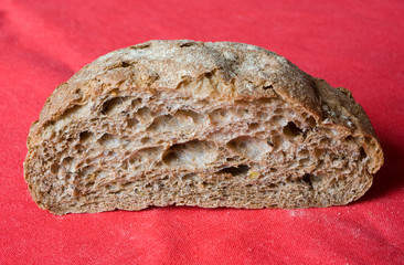 Half of fresh baked homemade bread on a red linen tablecloth
