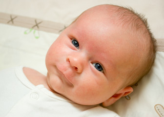 Smiling newborn boy with grey eyes is  laying on a blanket - 88461269