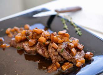 dish of pork with sauce on black plate