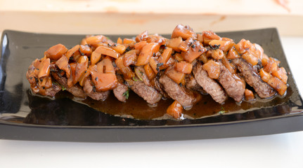 dish of pork with sauce on black plate