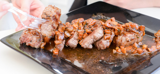 dish of pork with sauce on black plate