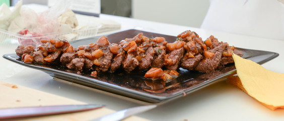 dish of pork with sauce on black plate