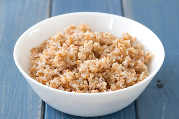 boiled cereals in bowl on blue wooden background