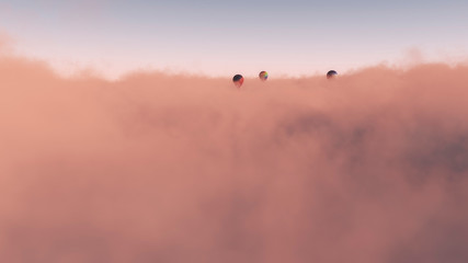 Three hot air balloons floating above dense cloud