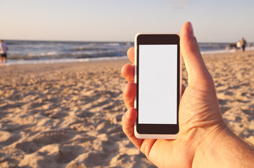 Man with smartphone in his hand on beach. Point of view.