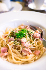 Spaghetti carbonara (with ham) on white plate