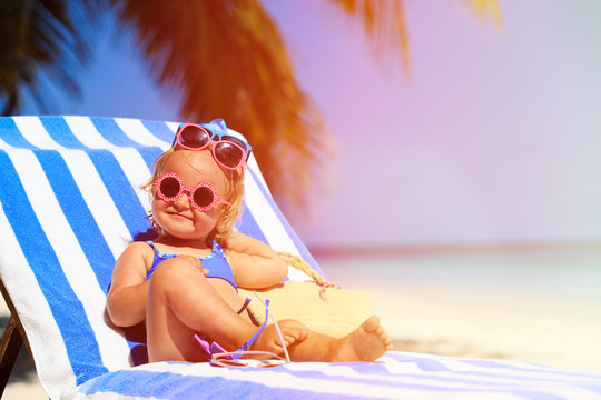 cute little girl trying on sunglasses at the beach