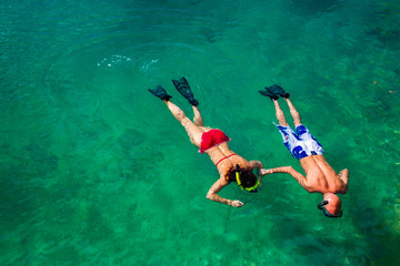Young couple snorkeling in clean water over coral reef