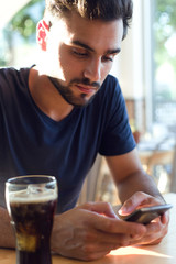 Modern young man with mobile phone in cafe.
