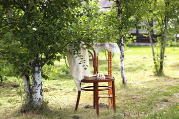 book on a chair in the park with tea and flowers