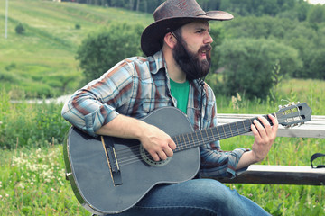 guitarist in a cowboy hat on the nature