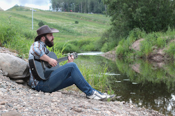 guitarist in a cowboy hat on the nature