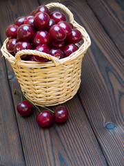 Fototapeta na wymiar Cherries in the basket on the dark textured wooden planks