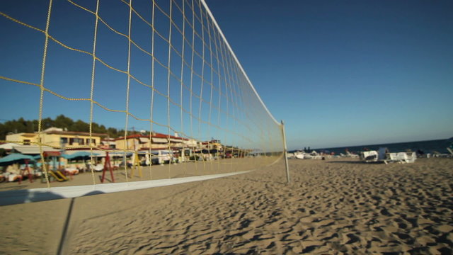 Beach Volleyball net sways in the wind on an empty beach at sunset