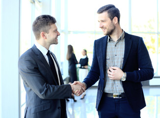 businesss and office concept - two businessmen shaking hands in