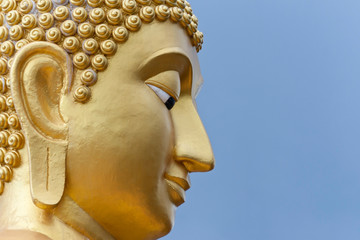 Golden Buddha head. Buddha statue on blue sky background.