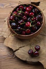 Bowl with sweet cherries over wooden background, selective focus