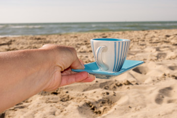 Cup of coffee under beach bbackground