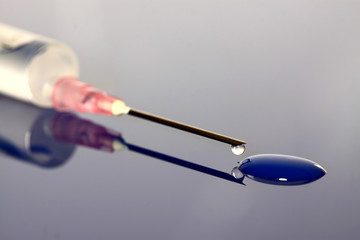 Syringe drugs.
Syringe with drugs on reflected blue surface.