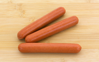 Three hot dogs on a cutting board.