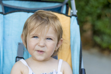 Portrait of adorable one year old baby girl riding in baby carri